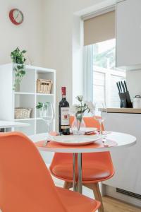 - une table avec 2 bouteilles de vin et des chaises orange dans l'établissement Modern Elegant Luxury 1 bed flat Free parking, 