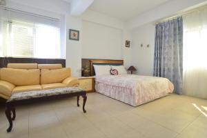 ein Schlafzimmer mit einem Sofa, einem Bett und einem Fenster in der Unterkunft 花蓮快樂腳旅宿近花蓮車站 in Hualien