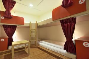 a bedroom with bunk beds with red curtains at CU Hotel Taipei in Taipei