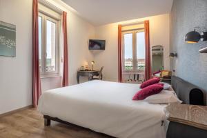 a bedroom with a large white bed with pink pillows at Hôtel d'Angleterre (by Popinns) in Vittel