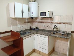 a small kitchen with a sink and a microwave at Departamentos San Pedro in San Pedro