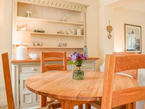 a dining room table with a vase of flowers on it at Hall Piece Cottage in Olney