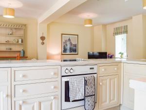 a kitchen with white cabinets and a stove top oven at Hall Piece Cottage in Olney