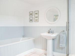 a white bathroom with a sink and a bath tub at Hall Piece Cottage in Olney