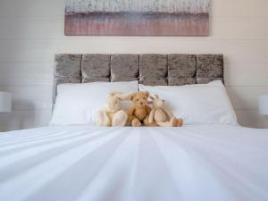 due orsacchiotti seduti sopra un letto di Lodge 10 - The Cedars a Perth