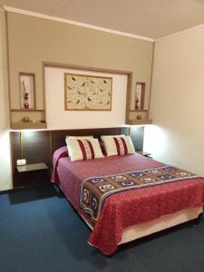 1 dormitorio con 1 cama con manta roja y almohadas en Departamentos San Pedro en San Pedro