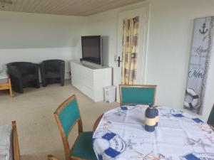 ein Esszimmer mit einem Tisch, Stühlen und einem TV in der Unterkunft Pension Küstenkind in Bentwisch