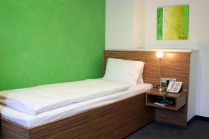 a bed with a telephone and a green wall at Hotel Restaurant Winkler in Mürzzuschlag