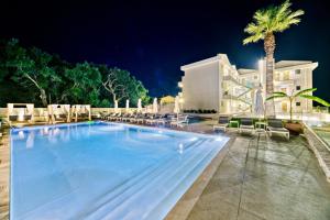 a large swimming pool with chairs and a building at Hidden Cove Corfu in Kontokali