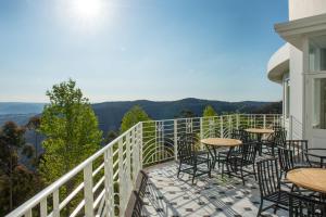 a balcony with tables and chairs and a view of the mountains at Hydro Majestic Blue Mountains in Medlow Bath
