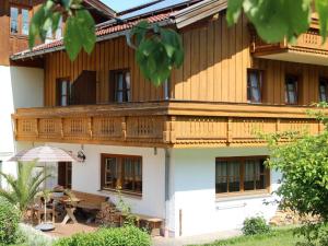 a large wooden house with a wooden balcony at Gästehaus Alpin - inkl. Chiemgau-Karte in Bergen
