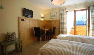 ein Hotelzimmer mit 2 Betten, einem Tisch und einem TV in der Unterkunft Gästehaus Alpin in Bergen