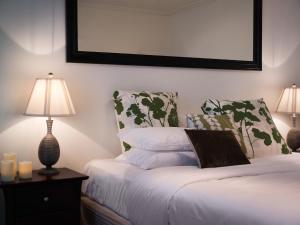 a bedroom with a bed with a lamp and pillows at Spa Villas on Main in Hepburn Springs