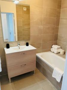 a bathroom with a sink and a bath tub and a mirror at Résidence-Chalet de Prestige Aspen Park - 103 in Auron