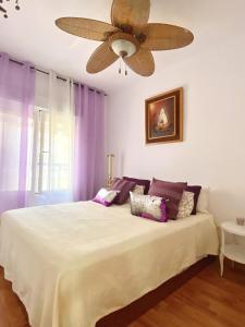 una camera da letto con un letto con tende viola e un ventilatore a soffitto di Rosario house a Santa Pola