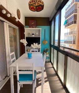 un tavolo bianco con sedie in una stanza con finestre di Rosario house a Santa Pola