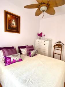 una camera da letto con un letto con cuscini viola e bianchi di Rosario house a Santa Pola