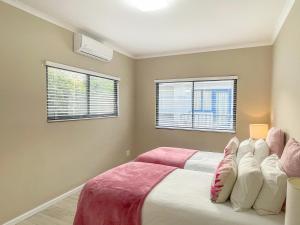 a bedroom with two beds and two windows at UysTUYS in Cape Town
