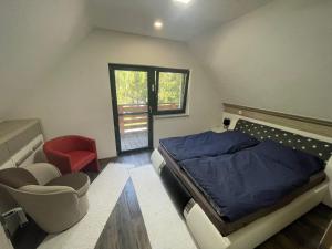 a bedroom with a bed and a chair and a window at Chata Miško in Snina