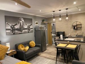 a living room with a couch and a kitchen at Leafy Retreat Kenridge Trendy in Durbanville