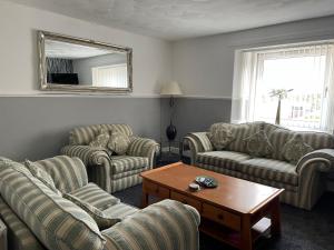 a living room with couches and a table and a mirror at Clarkes 1st floor Apartment Leslie- Golf Paradies in Leslie