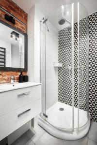 baño blanco con ducha y lavamanos en Apartamenty Piotrkowska 37 Loft w Centrum Łodzi Klimatyzacja en Lodz