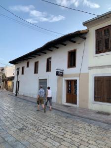 dos personas caminando en frente de un edificio blanco en Rooms for Rent, en Shkodër