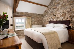 Shepherds Retreat في هيكسهام: غرفة نوم بسرير كبير وجدار حجري