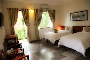 1 dormitorio con 2 camas y ventana en Charming Homestay, en Hoi An