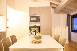 a white kitchen with a white table and chairs at Dascio Salute Ferienwohnung mit Panorama Balkon am See in Dascio