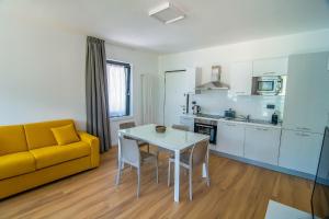 ein Wohnzimmer mit einem Tisch und einem gelben Sofa in der Unterkunft Dascio Oasi Ferienwohnung Dachterrassen am See in Dascio