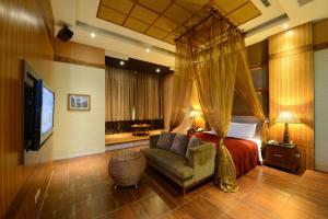 1 dormitorio con cama, sofá y TV en Shantis Motel en Chiayi