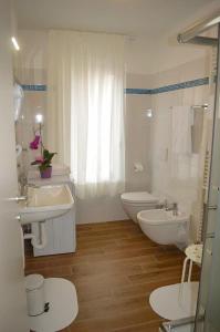a white bathroom with two sinks and a toilet at Miralago Stupendo Ferienwohnung I. Stock in Gravedona