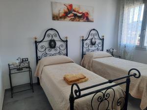 a bedroom with two beds and a picture on the wall at CENTRAL ROOMS TORTOLI' in Tortolì