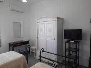 a bedroom with a white cabinet and a tv at CENTRAL ROOMS TORTOLI' in Tortolì