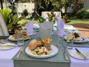 a table with plates of food and a bottle of wine at Burley House by Ulendo in Lilongwe