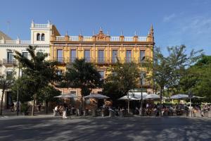 un gran edificio amarillo con gente sentada bajo sombrillas en numa I Prestigio Apartments en Sevilla