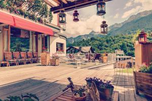 a patio with tables and chairs and mountains in the background at Hotel Tremoggia in Chiesa in Valmalenco