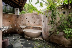 a bathroom with a bath tub next to a wall at Yabbiekayu Eco-Bungalows in Yogyakarta