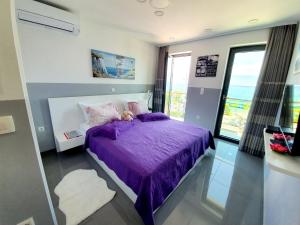 a bedroom with a purple bed with a large window at Apartments Toni in Baška