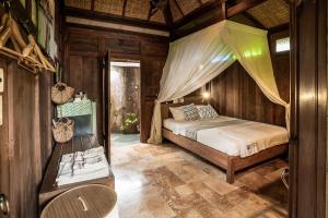 a bedroom with a bed and a table in it at Yabbiekayu Eco-Bungalows in Yogyakarta