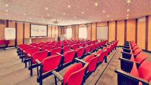 an empty lecture room with red chairs and a screen at Hotel Tremoggia in Chiesa in Valmalenco +37 photos
