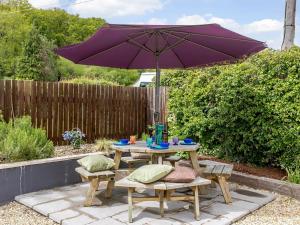 a picnic table and chairs with an umbrella in a backyard at Lilac Lodge in Flaxley