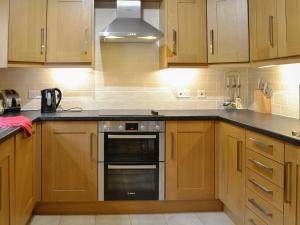 a kitchen with wooden cabinets and a stove top oven at Bridge Street Close in Cockermouth