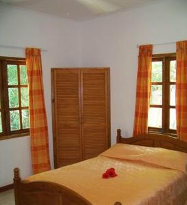 a bedroom with a bed with a red rose on it at Chalets Anse Possession in Baie Sainte Anne