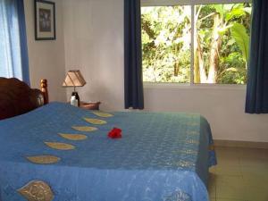 a bedroom with a blue bed with a red flower on it at Chalets Anse Possession in Baie Sainte Anne