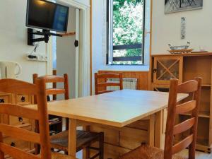 mesa de comedor de madera con sillas y TV en Appartement Cauterets, 3 pièces, 4 personnes - FR-1-234-139, en Cauterets