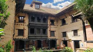 Newa Chen Historic House UNESCO في باتان: مبنى من الطوب القديم به نوافذ ونخلة