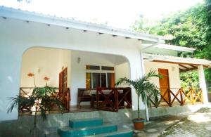 Casa blanca con porche y mesa en Chalets Anse Possession en Baie Sainte Anne