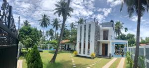 biały dom z palmami na dziedzińcu w obiekcie The Pearl w mieście Marawila